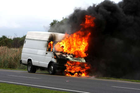 Delivery type vehicle on side of road burning with large flames and smokeの写真素材