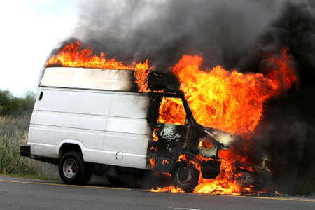 Delivery type vehicle on side of road burning with large flames and smokeの写真素材