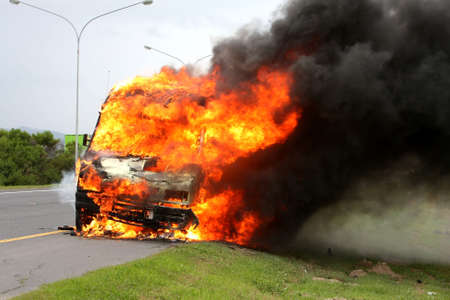 Delivery vehicle burning on the side of the road with huge orange flamesの写真素材