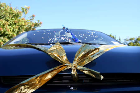 Wedding car decorated with gold bow and confettiの写真素材