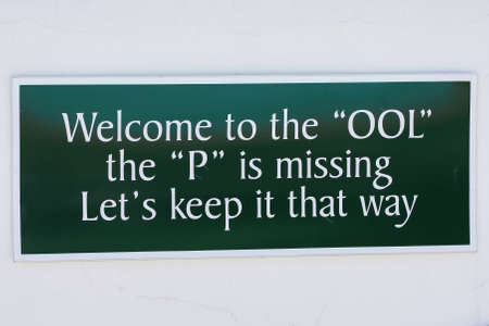 Funny sign mounted on a wall above a swimming poolの写真素材