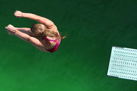 Diver above green water with end of diving board visibleの写真素材