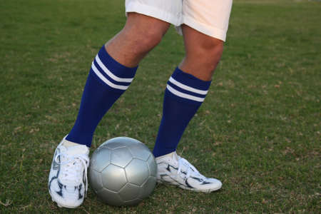 Soccer players legs in position to kick the ball