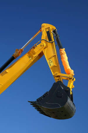 Black digging bucket on the end of a yellow hydraulic arm of a digging machineの写真素材