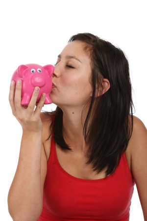 Pretty brunette woman kissing a pink piggy bankの写真素材