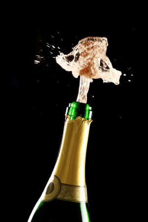 Champagne bottle with cork bursting out and sprayの写真素材