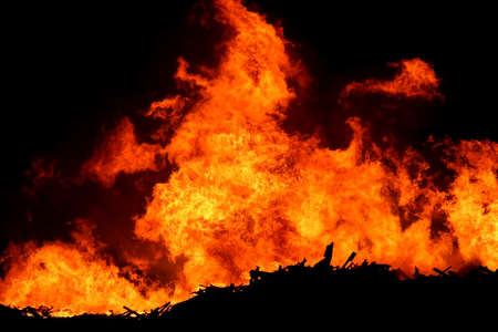 A huge fire with bright orange flames and silhouetted timber
