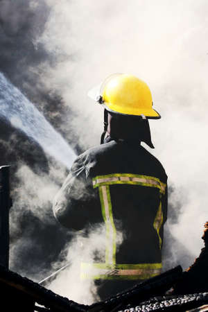 Fireman spraying water in a smouldering burnt out houseの写真素材