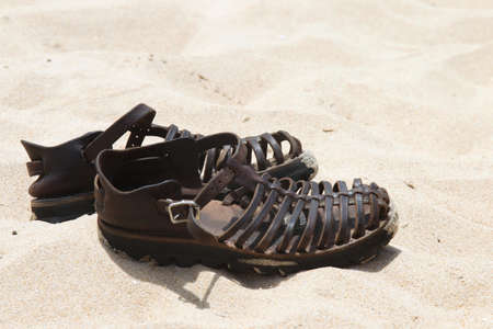 Leather sandals on the beach sand at the coast