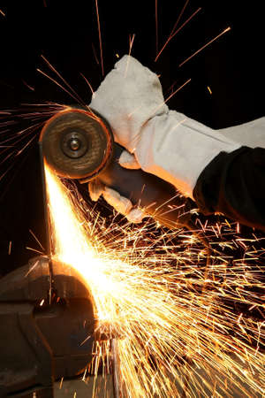 Shower of orange sparks from a worker grinding steel
