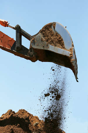 Industrial excavator machine scooping up sand and rocksの写真素材