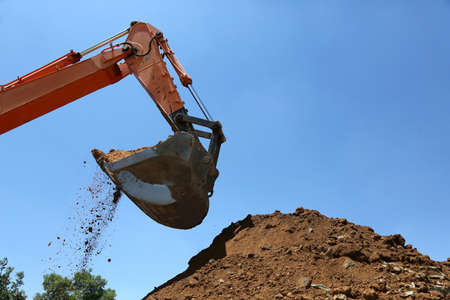 Industrial excavator machine scooping up sand and rocksの写真素材