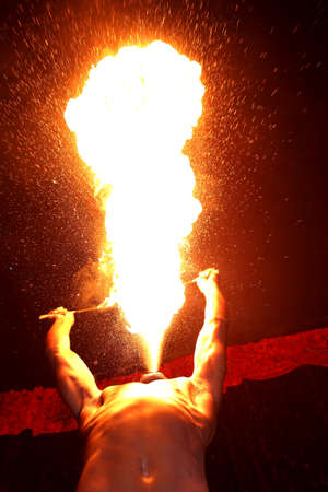Circus fire-eater blowing a large flame from his mouthの写真素材