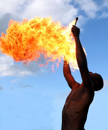 Circus fire-eater blowing a large flame from his mouthの写真素材