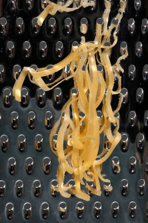 Close up of cheese grated on a stainless steel kitchen graterの写真素材