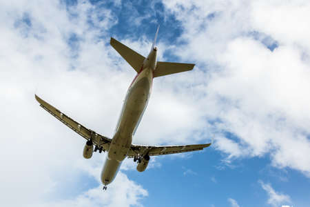 Passenger Jet Aircraft Flying Overhead against Cloudy Skyの写真素材