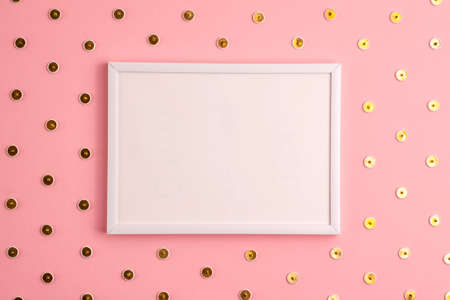 Mockup of white frame and gold colored push pins pattern around it on pink background. Flat lay top...