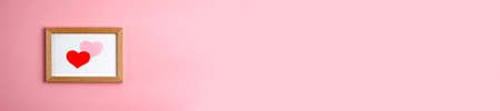 Banner of red and pink paper hearts in wooden frame on pink background at the left side. Valentine's...