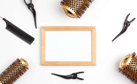 Mockup wooden frame flat lay of tree professional gold round hair brushes for styling,comb for separating hair and section hair clips template. Hairdresser salon equipment concept, premium set.の写真素材