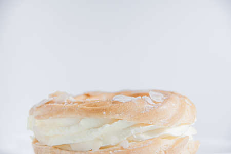 Ring donut cut in the middle and inside whipped cream and on the top almond slices and sugar puder...