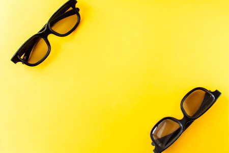 View from above of two pairs 3D black glasses on yellow background. Flat lay, cinema concept with copy spaceの写真素材