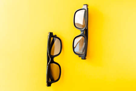 View from above of two pairs 3D black glasses on yellow background. Flat lay, cinema concept.の写真素材