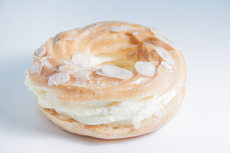 Ring donut cut in the middle and inside whipped cream and on the top almond slices and sugar powder...