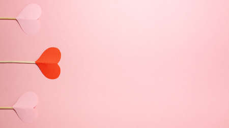 Banner of red and pink paper hearts on wooden sticks on pink background at the left side. Valentines day, love and romantic concept. Flat lay top view with copy spaceの写真素材