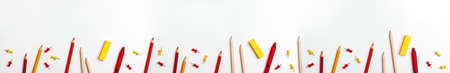 Red and yellow pen banner, sticky note, notepad, marker, eraser, push pins, paper clip pencils on the bottom on white background flat lay top view Education back to school online study concept copy spaceの写真素材