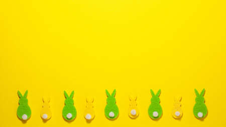 Yellow and green velvet bunnies on yellow background at the bottom with copy space. Flat lay top view. Easter conceptの写真素材