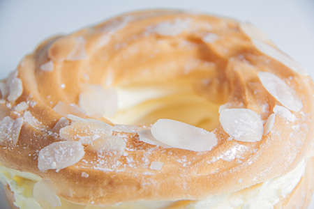 Ring donut cut in the middle and inside whipped cream and on the top almond slices and sugar puder...