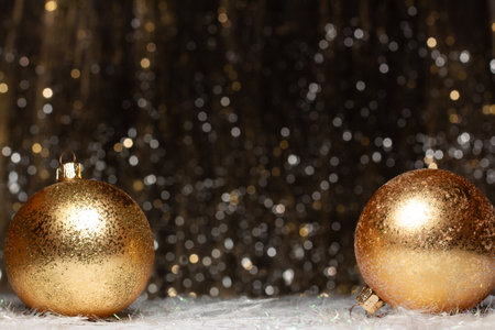 Christmas decorations composition view of two gold evening balls with gold glitter on it of the right and left site on dark background with silver and gold colors bokeh. Holiday concept with copy spaceの写真素材