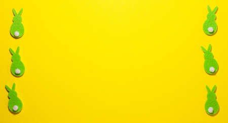 Green velvet bunnies on yellow background on the left and right side with copy space. Flat lay top view. Easter concept.の写真素材