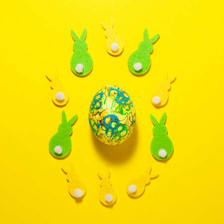 Yellow and green velvet bunnies and Easter egg in the center of the frame on a yellow background....
