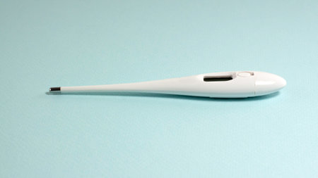White thermometer on a blue background with copy space.