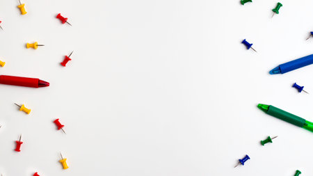 Yellow red blue green push pins and pens at the left and right on white background. Flat lay top view. Education back to school and online study conceptの写真素材