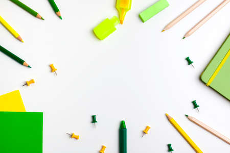 Green and yellow pen, sticky note, notepad, marker, eraser, push pins, paper clip pencils on white background. Flat lay top view. Education back to school and online study conceptの写真素材