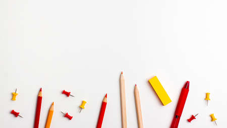 Red and yellow pen, sticky note, notepad, marker, eraser, push pins, paper clip pencils on the...