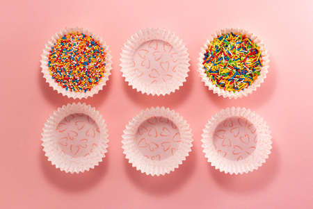 Cupcake liners with colored sugar inside and without it from above. Flat lay top view. Confectionery cooking concept on bright pink paper backgroundの写真素材