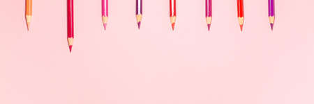 Banner of red, pink, purple, and orange pencils extend up and back two at a time at the top flat lay top view on crayon background with copy space. Education conceptの写真素材
