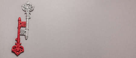 Red and silver vintage keys with glitter on gray background on the left side. Flat lay top view with copy space bannerの写真素材