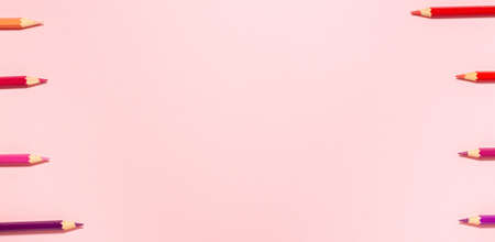 Banner of red, pink, purple, and orange pencils move forward two at time at the left and right clap their teeth flat lay top view on crayon background with copy space.の写真素材
