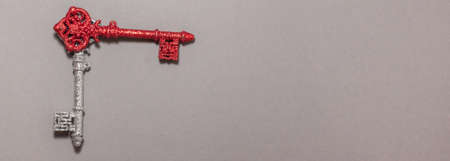 Red and silver vintage keys with glitter interpret clock hands on gray background on the left side. Flat lay top viewの写真素材