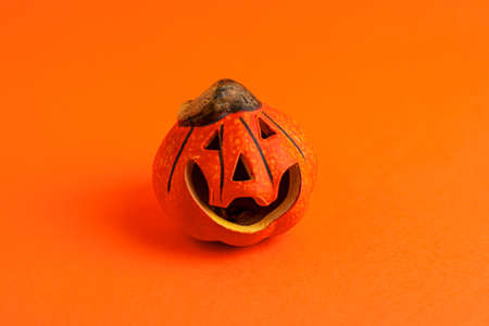 Decoration orange small smile Halloween pumpkin on orange blurred background and copy space. Holiday autumn concept backdrop.の写真素材
