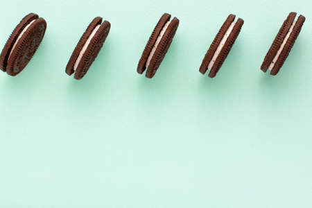 Sweet brown cookies with white cream inside on bright blue background at the top. Close up with copy space. Homemade and bakery conceptの写真素材