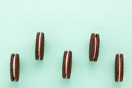 Sweet brown cookies with white cream inside on bright blue background at the bottom. Close up with copy space. Homemade and bakery conceptの写真素材