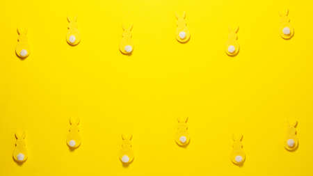 Yellow velvet bunnies on yellow background at teh top and battom with space for text. Flat lay easter and kids party coceptの写真素材
