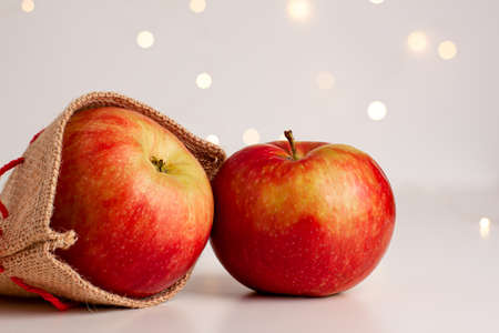 Close up of red yellow apples in a small bag with red string on bright background with yellow gold bokeh behind. Healthy organic food, autumn mood and still life concept with copy spaceの写真素材
