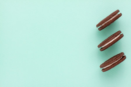 Sweet brown cookies with white cream inside on bright blue background. Close up with copy space. Homemade and bakery conceptの写真素材