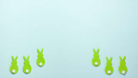 Green velvet bunnies with white tails on bright blue background at the bottom with copy space. Flat lay top view. Happy Easter concept templateの写真素材